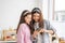 Mixed race girl younger and older sister talk and smile while play and using smartphone inside of the kitchen in the morning while