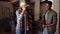 Mixed race male and female farmers working in shed sweeping dirty floor while chatting