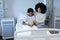 Mixed race mother comforting her sick daughter holding teddy bear in hospital bed