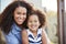 Mixed race mother and young daughter smile to camera outside