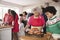 Mixed race, multi generation family gathered in kitchen before Christmas dinner, grandmother and grandson preparing roast turkey i