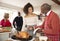 Mixed race senior and young adult family members talking in the kitchen while preparing Christmas dinner together, close up