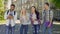 Mixed-race students laughing looking into camera, standing on university campus