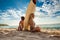 Mixed race surfer girls sitting back to back with surfboard in between