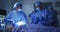 Mixed race surgeons wearing protective clothing looking at patient in operating theatre