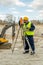 Mixed-race surveyor with tablet looking in lens of thedolite at construction site