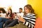 Mixed-race of technology addicted young friends serious looking at the smartphone at home on sofa without interacting with each