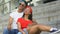 Mixed-race teenager couple hugging at stadium stairs, watching sport game