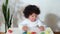 Mixed-race toddler little boy girl sits at the table and stacks wooden toys