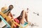 Mixed race woman on beach holiday sitting in deckchair using smartphone