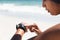 Mixed race woman exercising on beach checking smartwatch