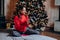 Mixed race woman in red sweater holding a gift against the background of a christmas tree