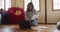 Mixed race woman working at home, kneeling on floor using laptop and holding paperwork in cottage