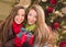 Mixed Race Young Adult Females Holding A Christmas Gift In Front