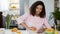 Mixed race young woman squeezing orange juice, weight and health control, diet