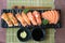 Mixed salmon sushi on black plate along with Japanese sauce and