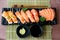 Mixed salmon sushi and sashimi on black plate along with Japanese sauce and green leaf decoration, Japanese food, close up at