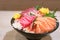 Mixed sliced fish sashimi on ice in black bowl. Sashimi Salmon Tuna Hamachi Prawn and Surf Calm set, raw fish, japanese food in