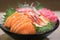 Mixed sliced fish sashimi on ice in black bowl. Sashimi Salmon Tuna Hamachi Prawn and Surf Calm set, raw fish, japanese food in
