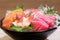 Mixed sliced fish sashimi on ice in black bowl. Sashimi Salmon Tuna Hamachi Prawn and Surf Calm set, raw fish, japanese food in