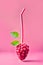 Mixed small raspberries in the shape of raspberry. Fresh red raspberries with drinking Straw on pastel pink background