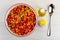 Mixed sweet pepper, carrot, green peas, corn in ceramic bowl, bottle of vegetable oil, salt, spoon on table. Top view