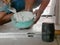 Mixed tile grout in a plastic bowl in a construction worker`s hands ready to be used for grouting ceramic tile floor