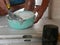 Mixed tile grout in a plastic bowl in a construction worker`s hands ready to be used for grouting ceramic tile floor - tiling wor