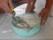 Mixed tile grout in a plastic bowl in a construction worker`s hands ready to be used for grouting ceramic tile floor - tiling work