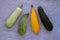 Mixed yellow, white, stripped and green zucchini`s on a grey concrete background