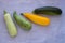 Mixed yellow, white, stripped and green zucchini`s on a grey concrete background