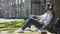 Mixed young male sitting under tree in headphones, eyes closed, enjoying music