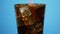 Mixing cold cola cocktail with drinking straw. Sparkling soda blue background