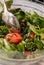 Mixing Fresh Green Salad with Arugula, Tomatoes, Tuna, Olive Oil, Avocado, Healthy Food. Vertical Image. Cooking Vegan food.