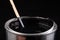 Mixing paint with a wooden stick in a metal can. Preparation of a black emulsion for painting