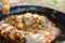 Mixing uncooked rice with tomato sauce spices and deep fried rabbit and chicken meat in large flat skillet. Preparing paella