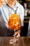 Mixologist decorates rosemary on the orange fruity cocktail that mix with sliced orange and lychee in a wine glass