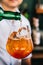 Mixologist pours liquor on the orange fruity cocktail that mix with sliced orange in a wine glass