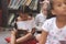 Mixte ethnicity schoolgirls holding digital tablet and sitting on cushions in a library