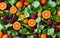 a mixture of cut and whole tangerines with berries on a green leaf