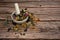 A mixture of various medicinal herbs in a porcelain mortar with a pestle on a wooden background.