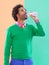 Mmmm...thats good. a stylish young man drinking from a bottle against a colorful background.