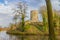 Moat with calm water with the tower of the Stein castle ruins on a hill, bare trees, climbing plants