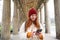 Mobile broadband and people. Smiling redhead 20s girl with backpack, uses smartphone on street, holds mobile phone and