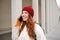 Mobile broadband and people. Smiling young redhead woman walks in town and talks on mobile phone, calling friend on