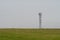 Mobile cell tower antenna mast providing mobile internet connection for rural area standing on empty barren field on grey overcast