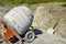 Mobile concrete mixer on background of pile of gravel. Preparatory work for preparation of concrete mass. Close-up.