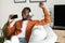Mobile karaoke application. Joyful african american man singing song while listening to music in wireless headphones