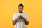Mobile offer. Happy african american guy holding smartphone and smiling over yellow studio background, free space