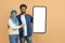 Mobile Offer. Young Muslim Couple Pointing At Blank Smartphone In Their Hands